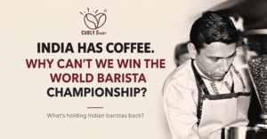 Black-and-white photograph of an Indian barista at work alongside the headline “India Has Coffee. Why Can’t We Win the World Barista Championship?” on a Curly Brew feature image.